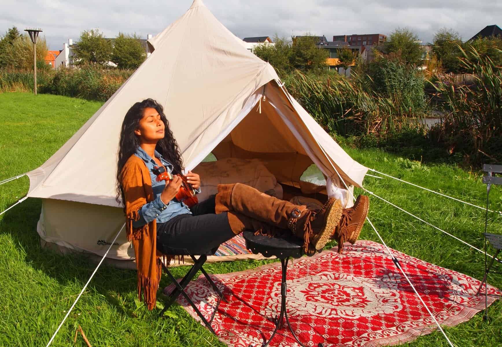 Gemütliche Zeltcamping-Szene mit Frau, die in der Natur entspannt und die Sonne genießt, perfekt für Outdoor- und Abenteuerliebhaber.