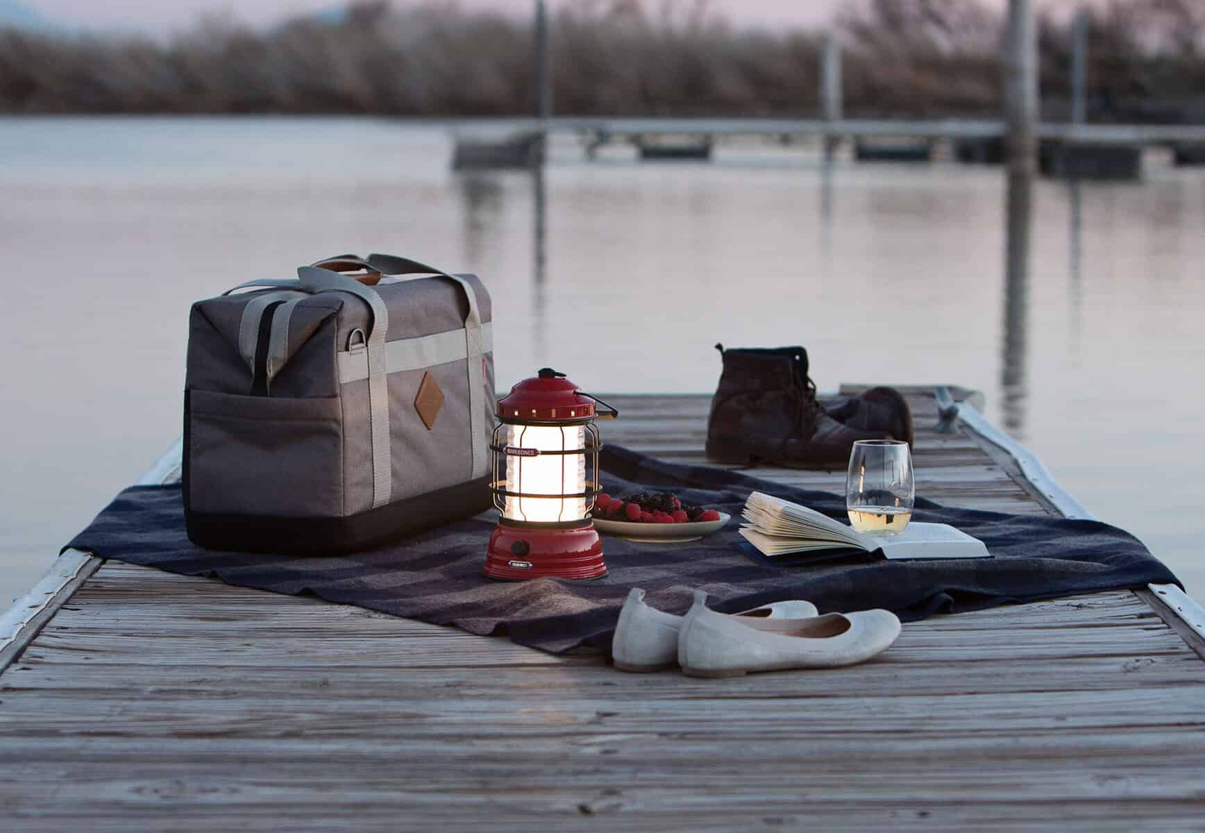 Rucksack, Boots, und Campingzubehör auf einem Steg am See, bereit für Outdoor-Abenteuer und Naturerkundungen.
