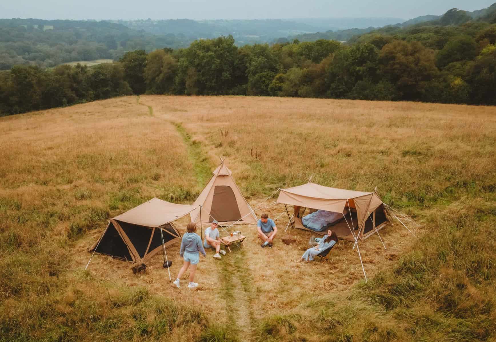 Abgelegene Zelten im Grünen, Camping im Freien, Naturerlebnis, Familie beim Camping in einer malerischen Landschaft, Zelte und Campingausrüstung in einer offenen Wiese.