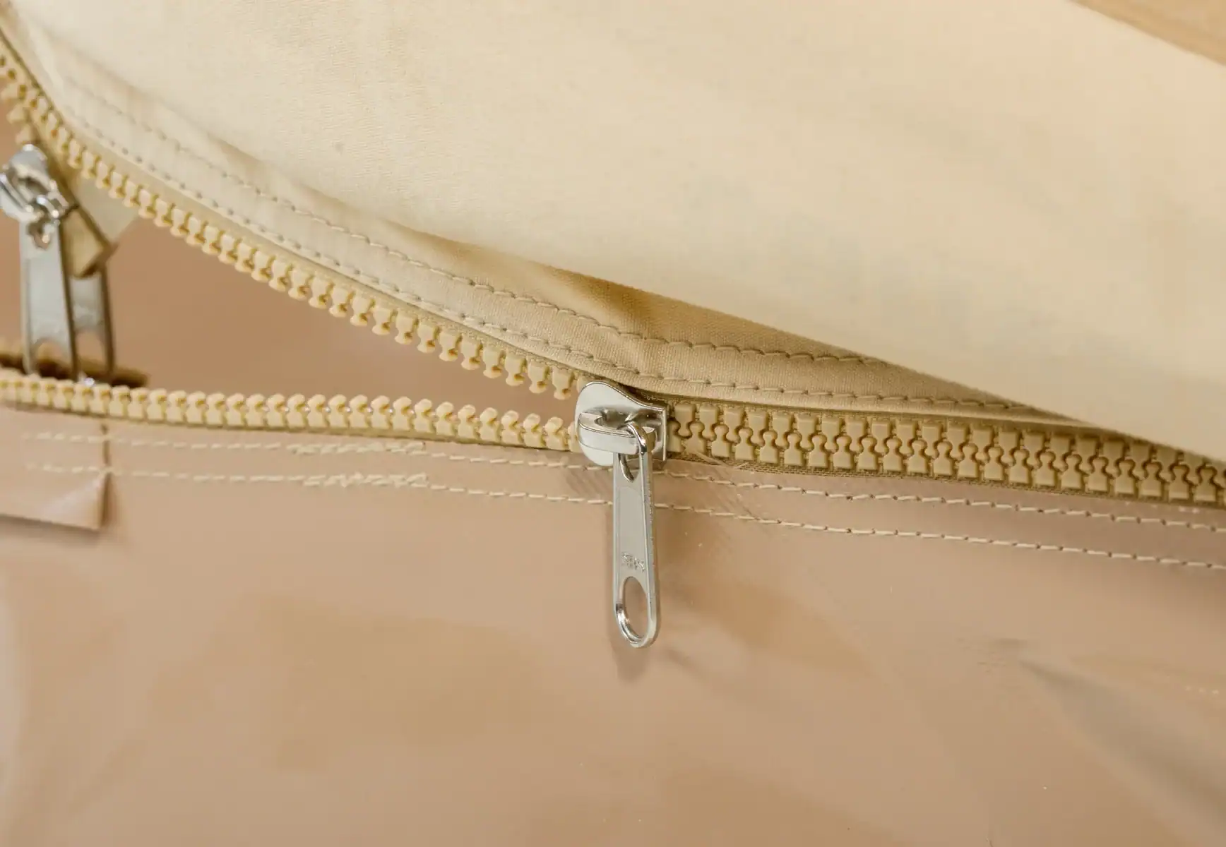 Hochwertiger beige Reißverschluss auf einer Tasche, Nahaufnahme, stilvoller Accessoire-Detail.