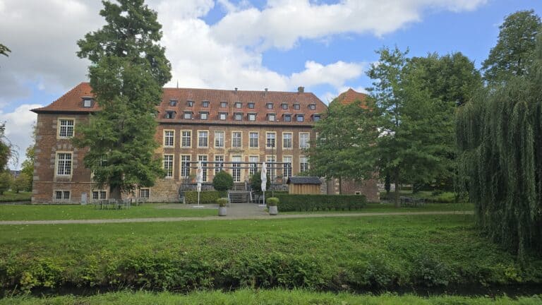 Historisches Gebäude bei Heiden umgeben von Bäumen und gepflegtem Garten, ideal für Natur- und Architekturinteressierte.